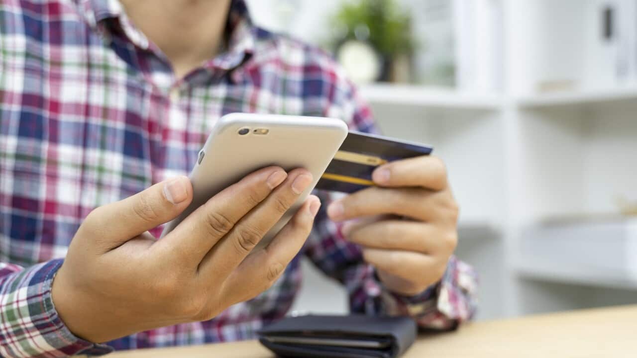 Young man hands holding credit card and using phone.