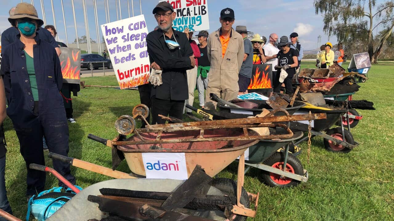 Bushfire survivors carry remnants of their properties in wheelbarrows outside Parliament House.