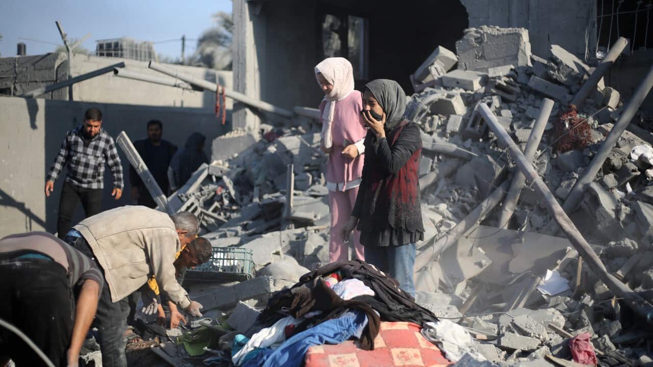 People stand on the rubble of their home after an airstrike.
