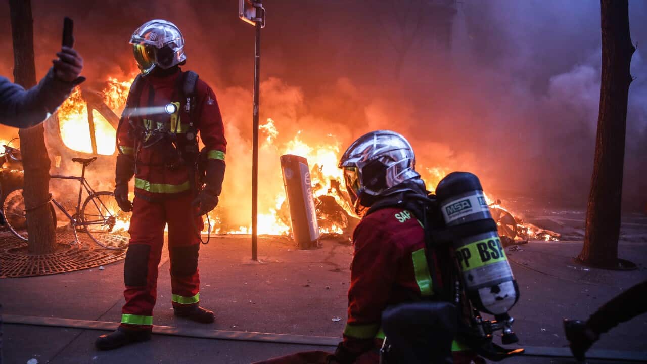 Firefighters prepare to extinguish a fire as several cars burn during a protest against France's controversial global security law in Paris on 5 December 2020.