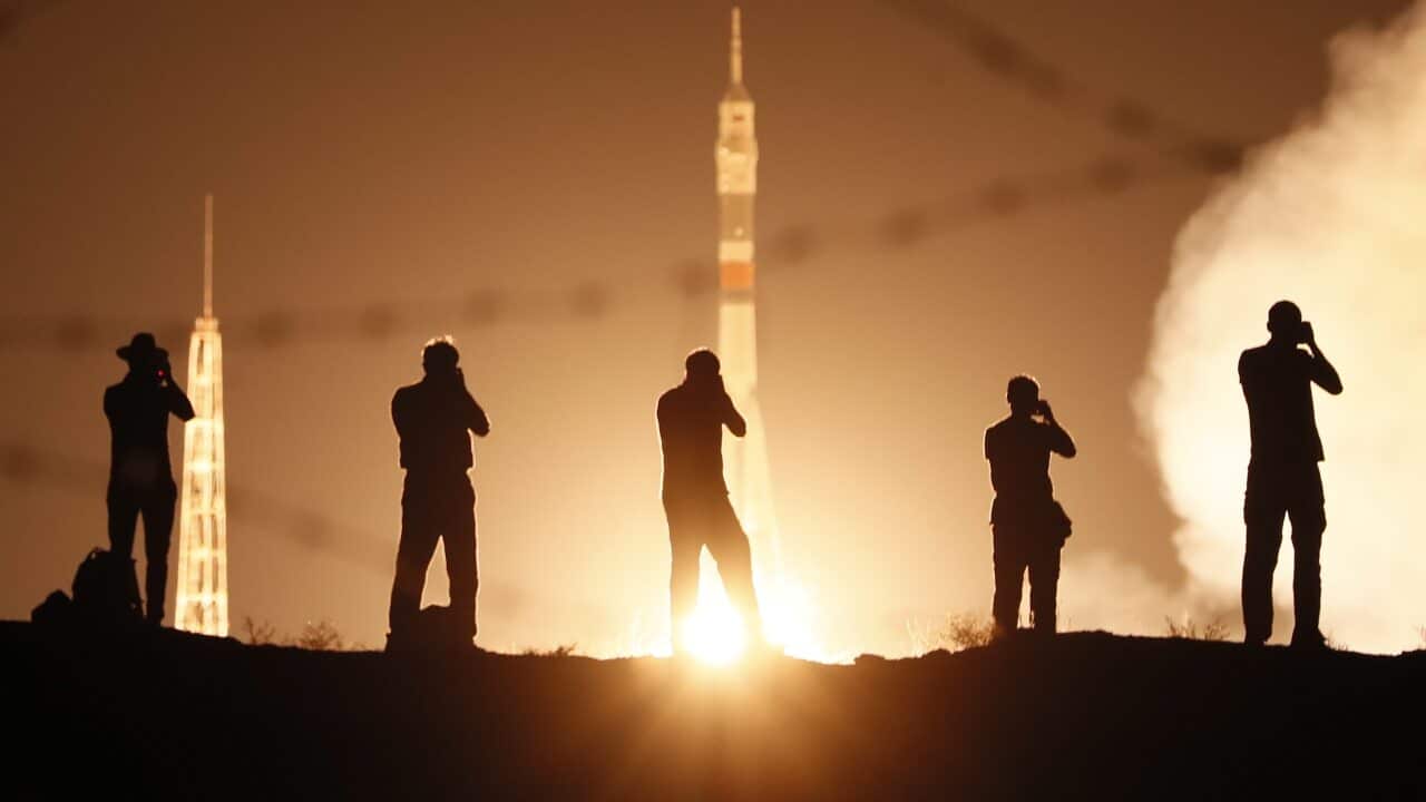 Media take photos as a spacecraft launches with members of the International Space Station expedition onboard.