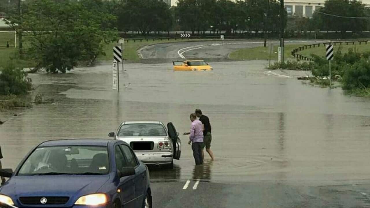 Vehicles drive through a flooded road in Rocklea, Brisbane.