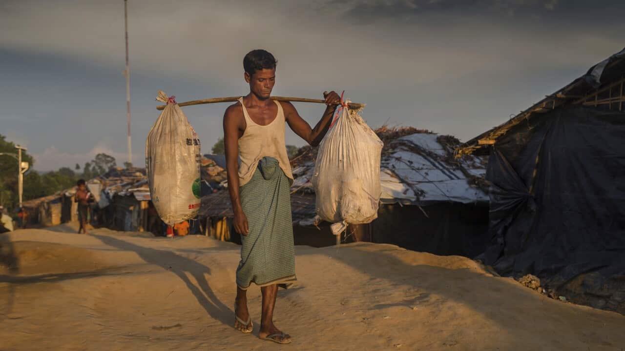 A Rohingya Muslim man carries his belongings as he arrives in Kutupalong refugee camp, Bangladesh.