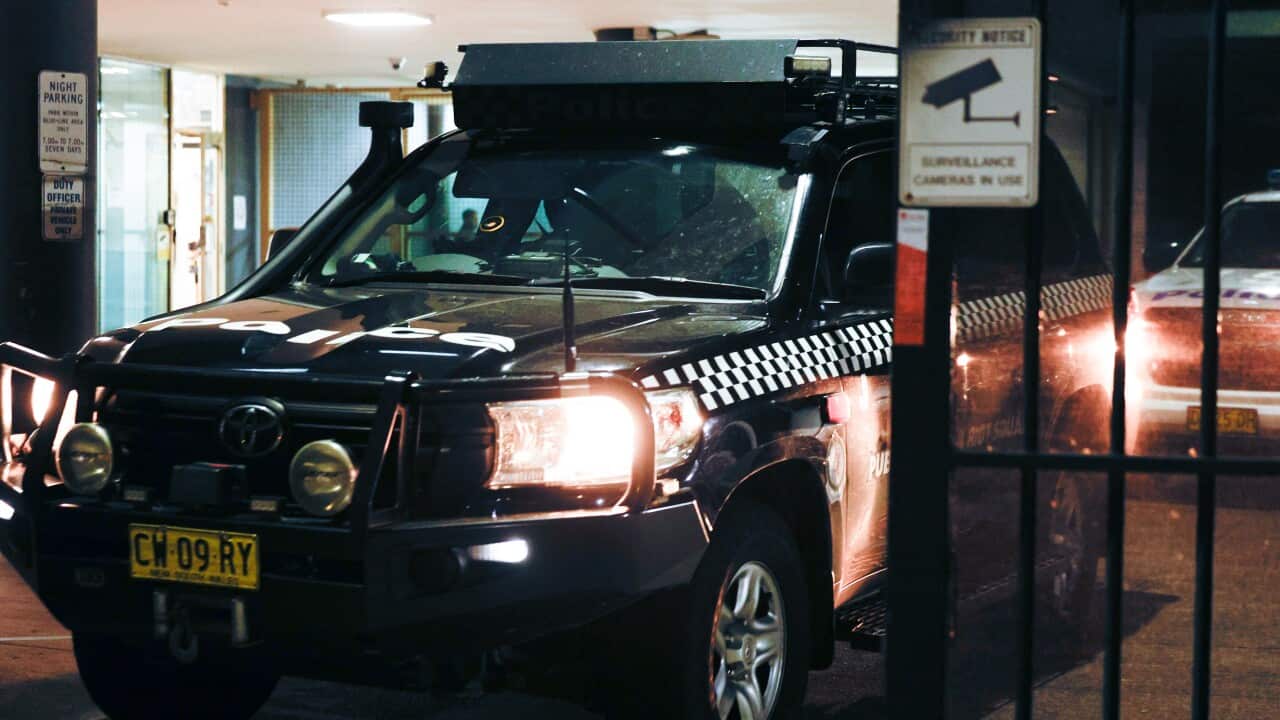 A police car passes through security gates at night.