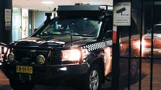 A police car passes through security gates at night.