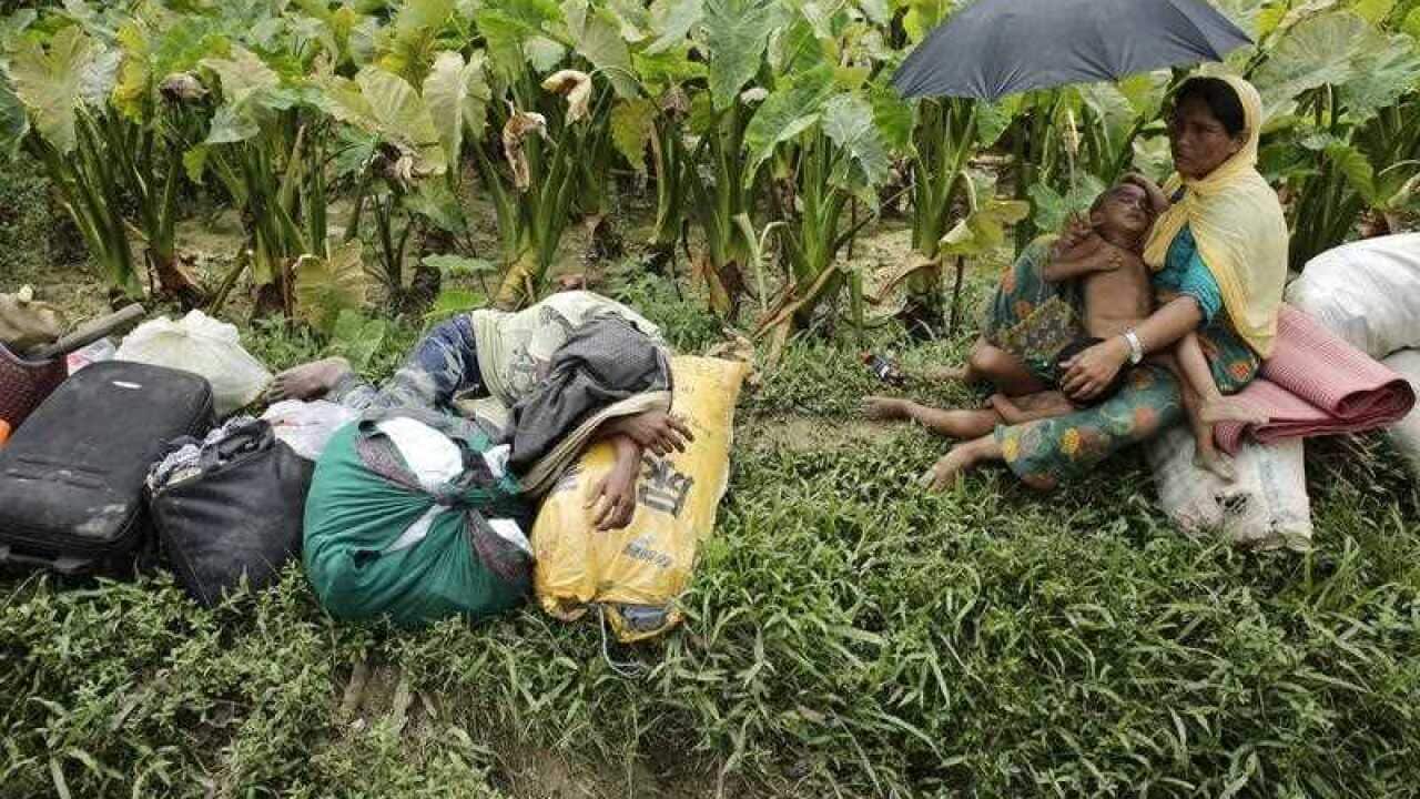 A Rohingya man sleeps on his belongings as a woman sits beside a street with her child in Ukhiya, Cox's Bazar, Bangladesh, 11 September 2017.
