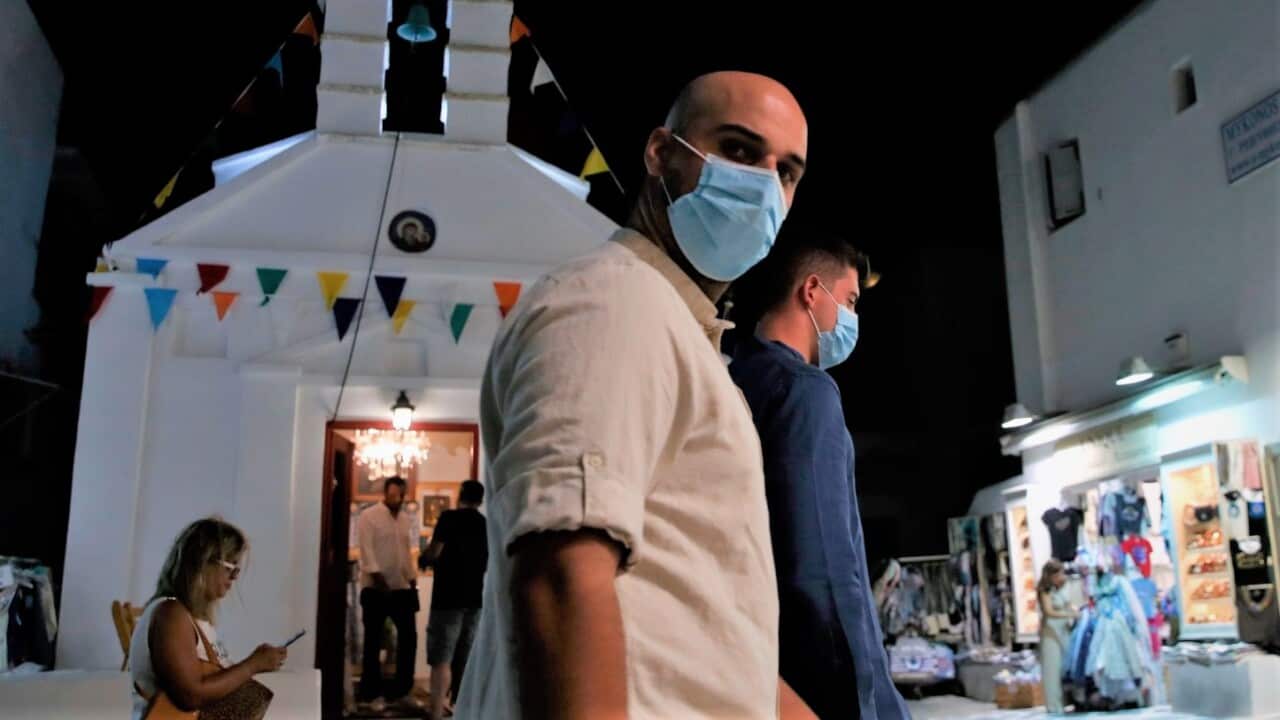 People wearing face masks against the spread on the new COVID-19 as they walk at the narrow streets of Matogiannia on the Aegean Sea island of Mykonos, Greece.