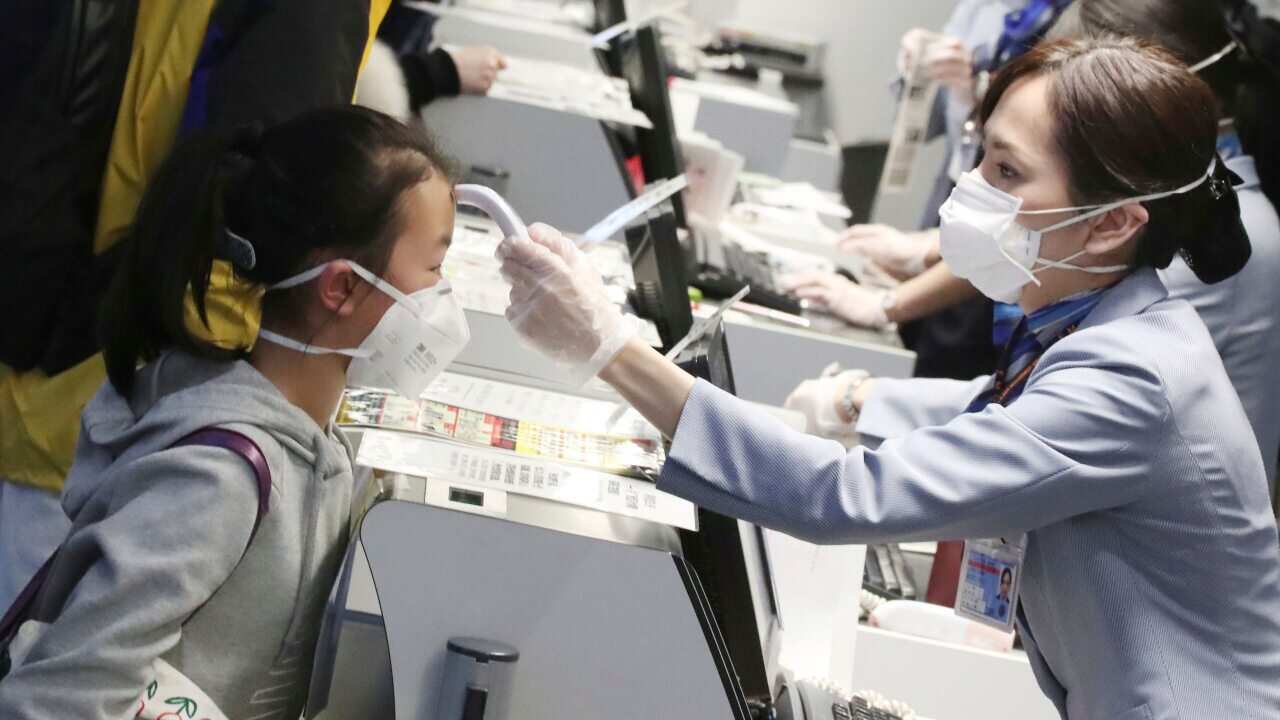 Passengers have their body temperature assessed by check-in staff ahead of a flight from Tokyo to the coronavirus epicentre of Wuhan, China.