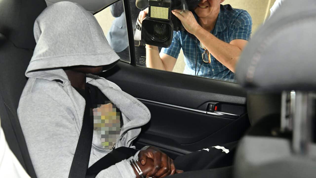 A man is seen being driven into the Brisbane Watchhouse by police.
