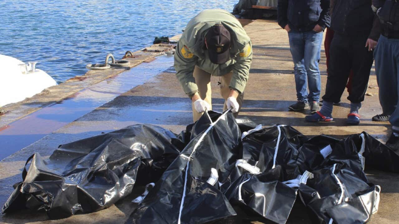 People check bodies of migrants at a port near Izmir, Turkey