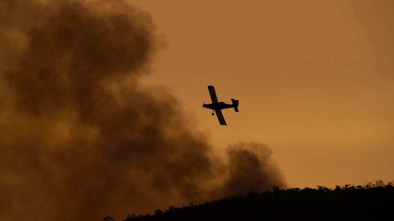 A small aircraft is pictured after dumping fire retardant behind houses at the foot of Mount Tennant, close to Canberra.