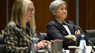 Senator Penny Wong looks concerned and frustrated while sitting behind a desk with a microphone