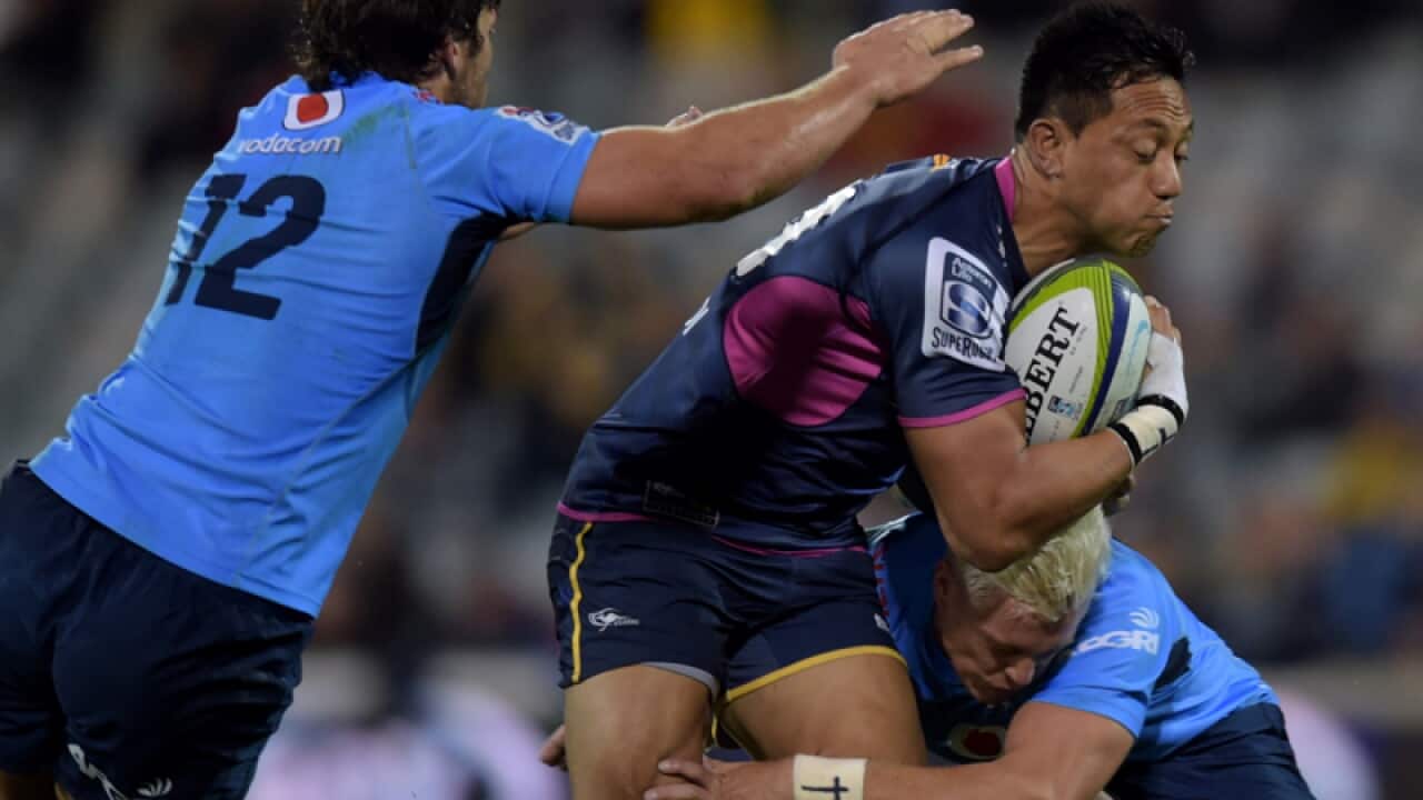 Christian Lealiifano of the Brumbies (centre) is tackled