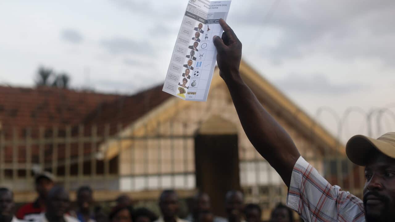 An electoral agent holds up a ballot paper as he counts votes while voters observe closely after the poll at a polling station in Kampala, Uganda, 18 February 2016. (EPA)