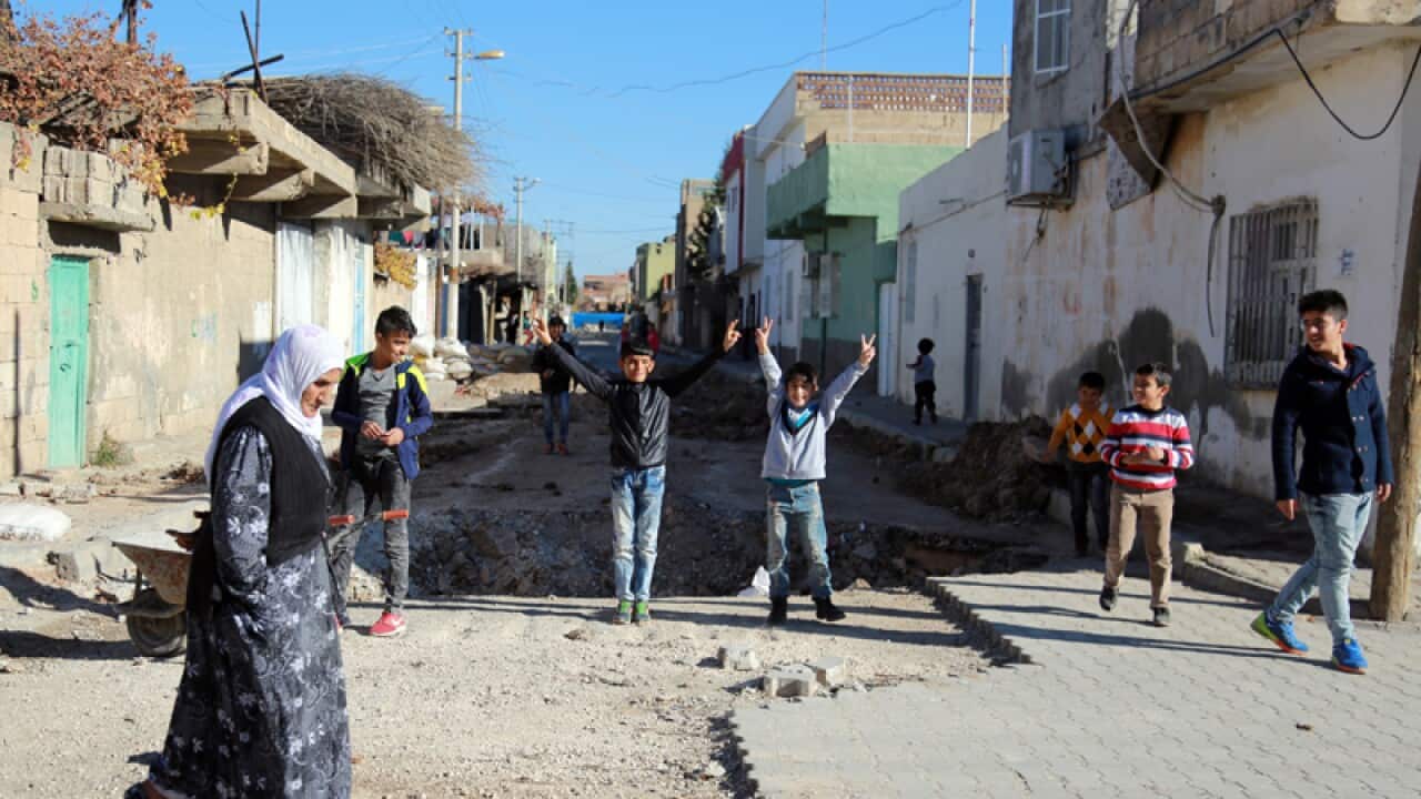 People walk through debris set up by Kurdish fighters in Turkey