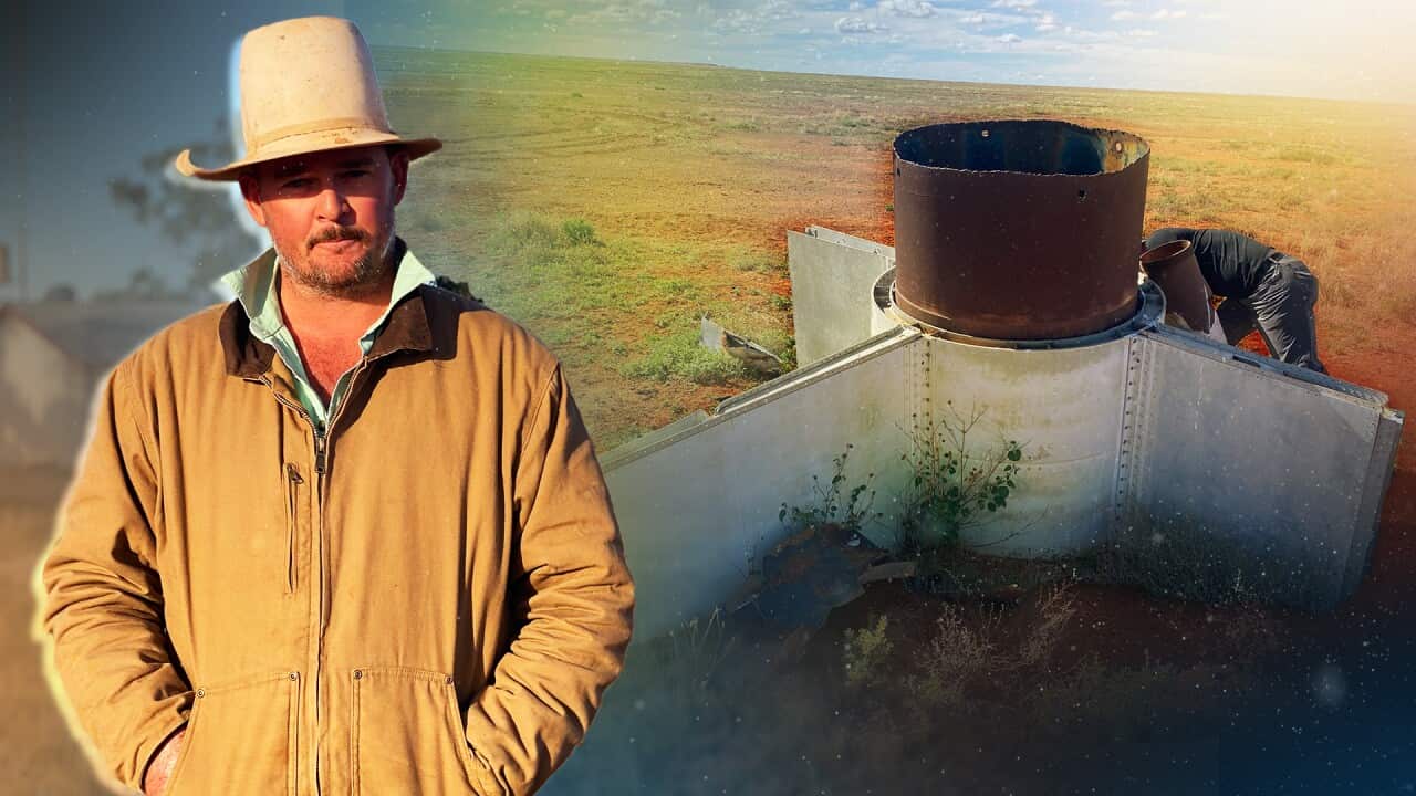 A man stands with an image of part of a rocket in the background.