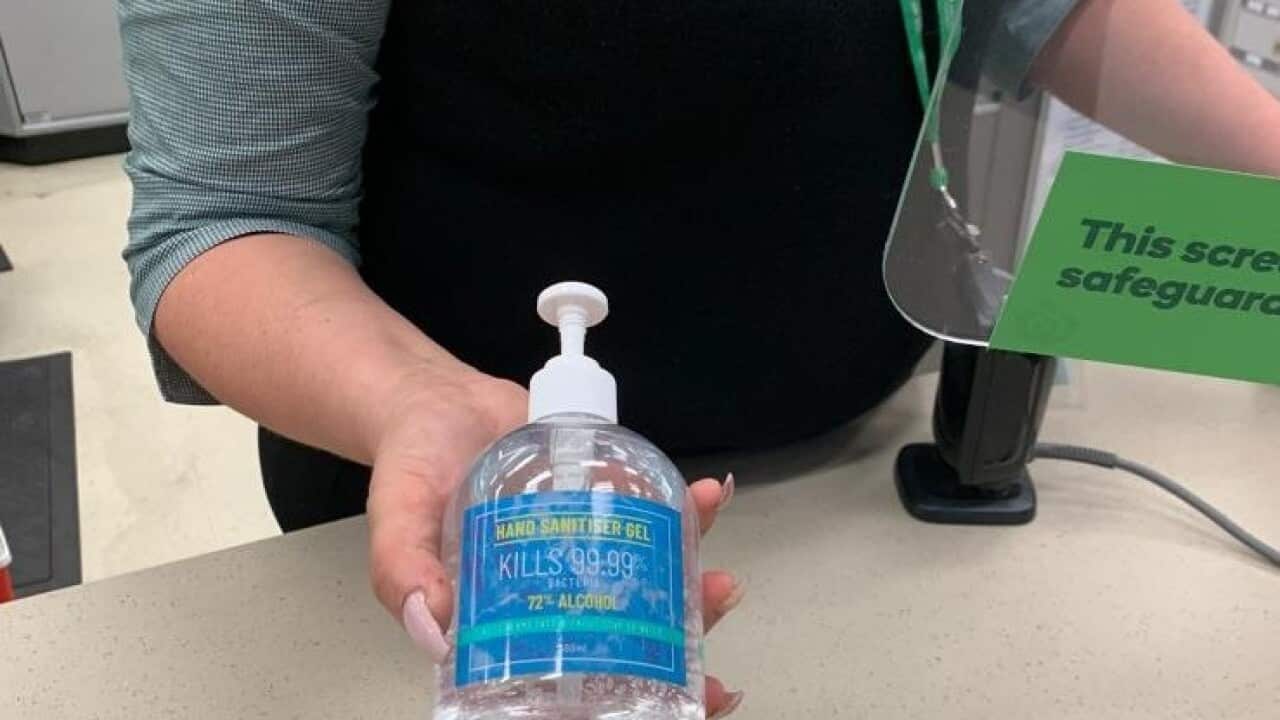 Woolworths staff member with hand sanitiser