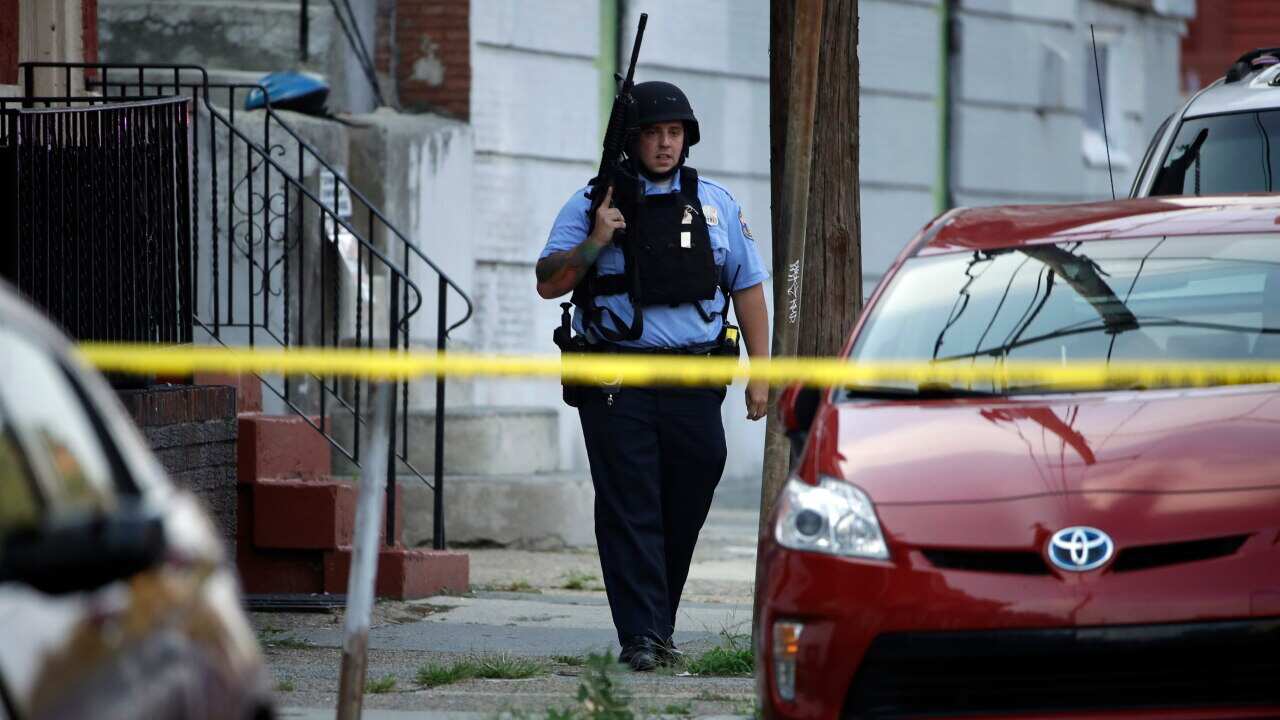 A police officer patrols the block near a house as they investigate an active shooting situation in the Nicetown neighborhood of Philadelphia.