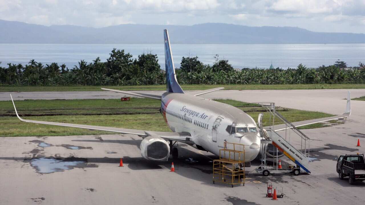 A Sriwijaya Air's airplane, covered with volcanic ash from the Mount Gamalama volcano eruption, parks on the tarmac of Sultan Babullah airport in Ternate, North Maluku, Indonesia, 19 December 2014. (AAP)