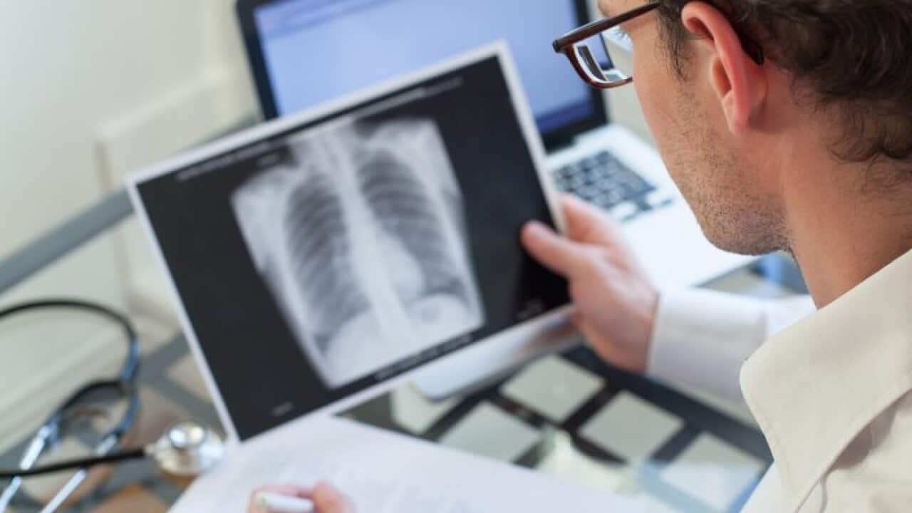 doctor looking at x-ray of lungs and writing diagnosis