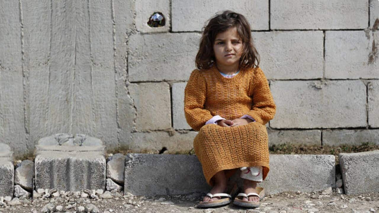 A displaced Syrian girl sits outside her family's tent at a refugee camp in Bar Elias, Bekaa Valley, Lebanon, Friday, March 5, 2021.
