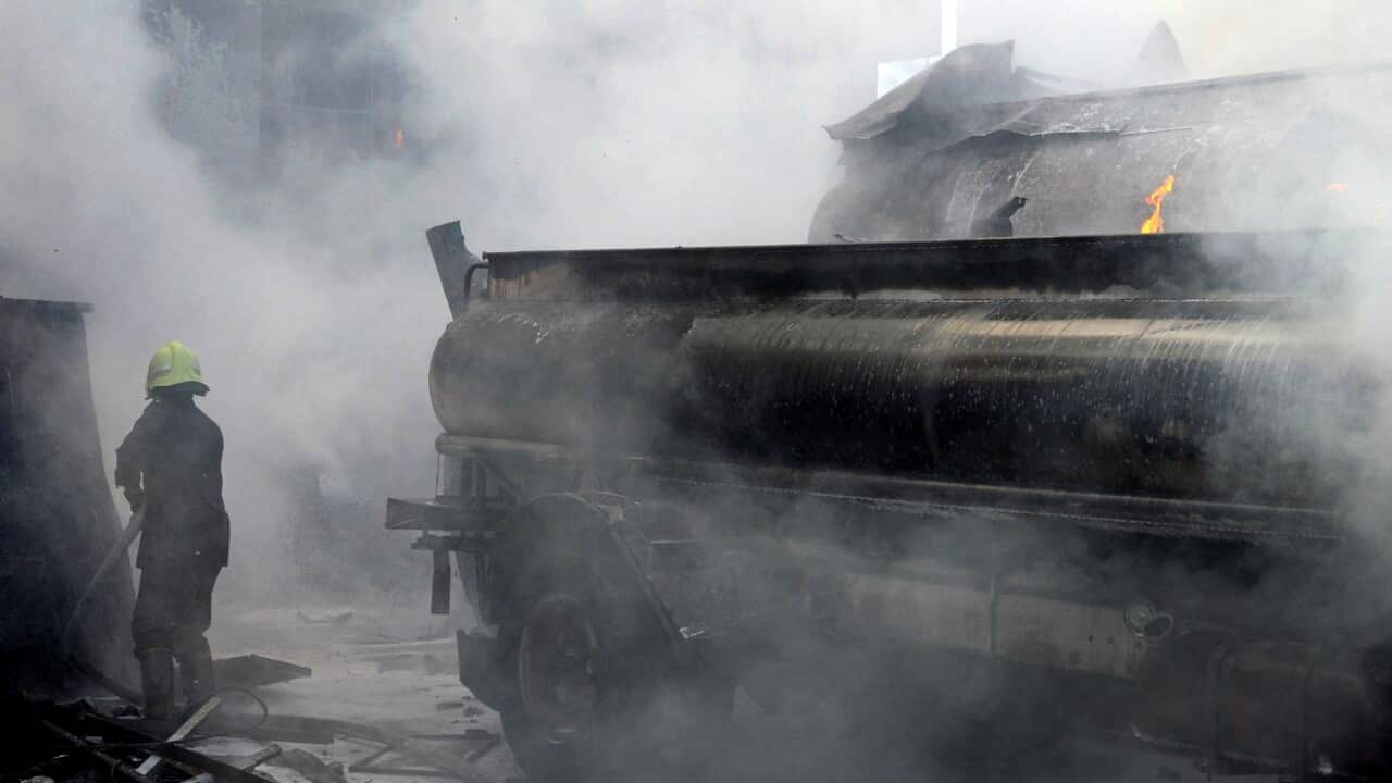 In this photo released by the Syrian official news agency SANA, a firefighter extinguishes fire at the scene after a bomb attached to a fuel truck exploded.