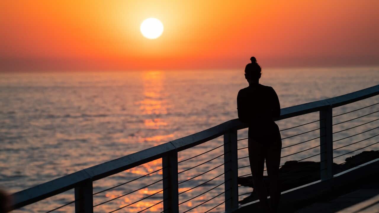 A woman watches as the sun rises over the ocean at Bronte Beach in Sydney, Friday, October 25, 2019. Temperatures are forecast to reach as high as 36 degrees in Sydney today. (AAP Image/James Gourley) NO ARCHIVING