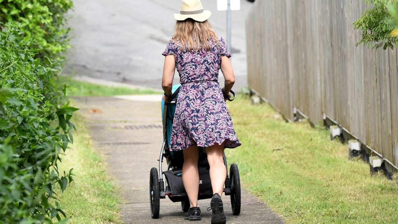 A mother pushes a stroller after picking up her child early from childcare in Brisbane.
