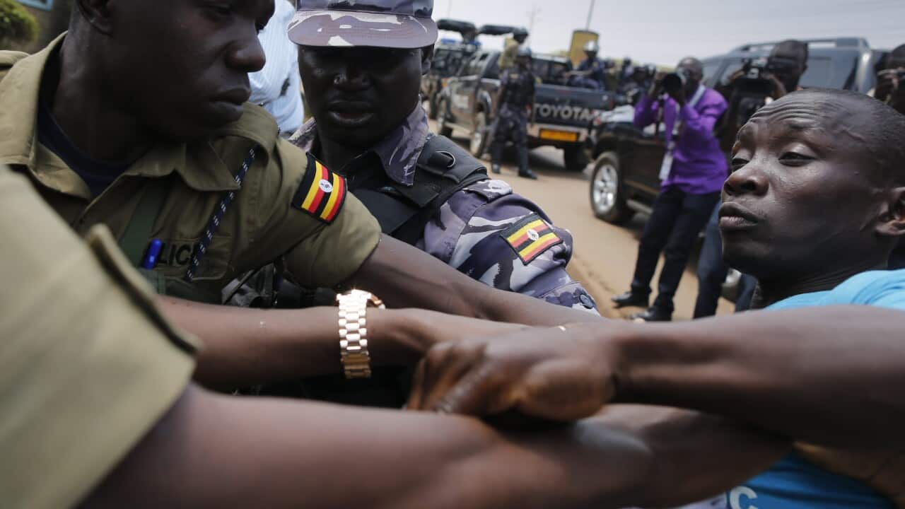 A supporter of Kizza Besigye, the leader of the main opposition Forum for Democratic Change (FDC) and the main opposition candidateate, fights with police officers trying to close the gate to lock them inside Besigye's party headquarters in Kampala, Ugand