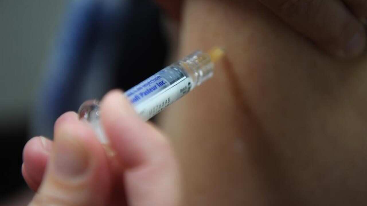 A woman is seen receiving a flu immunisation