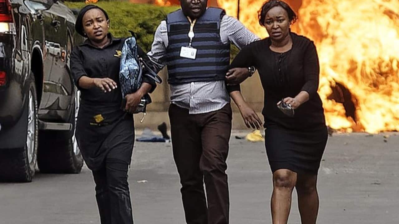 A member of Kenya's security forces helps civilians.
