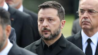 Zelensky in a black coat looking serious.