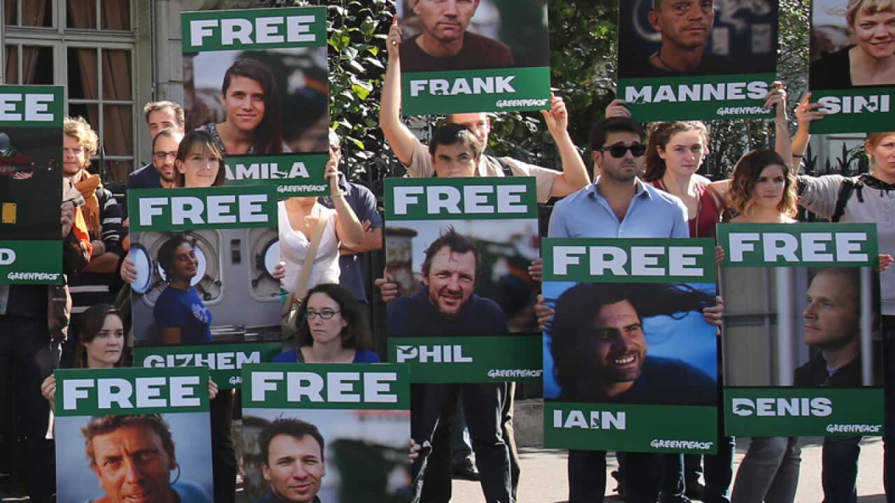 Activists hold signs protesting the jailing of Greenpeace activists