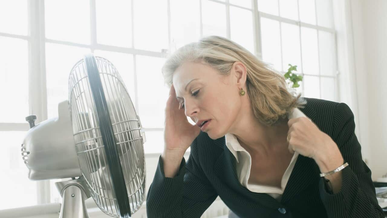 Hot businesswoman sitting in front of fan