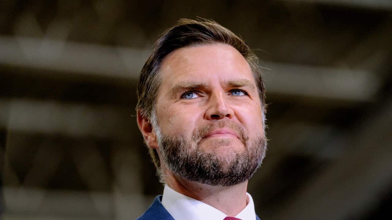 JD Vance, wearing a blue blazer, white shirt and red tie.