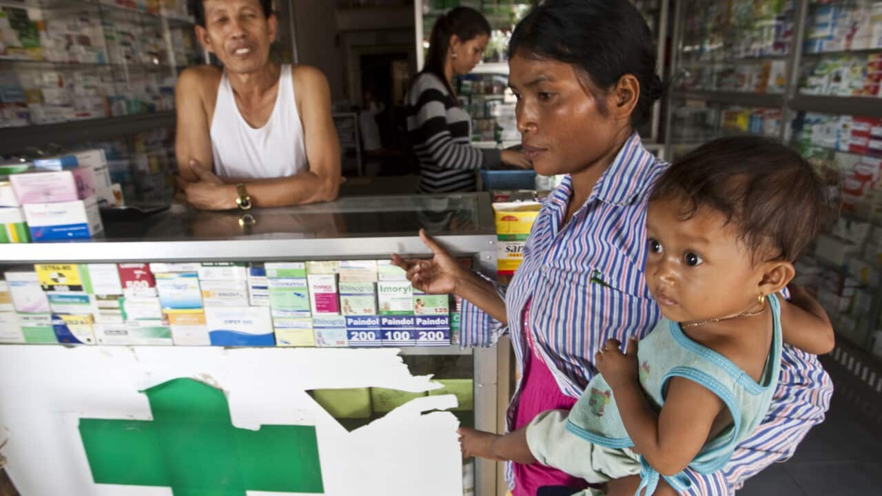 A woman holding her ill child at a pharmacy in Pailin, Cambodia