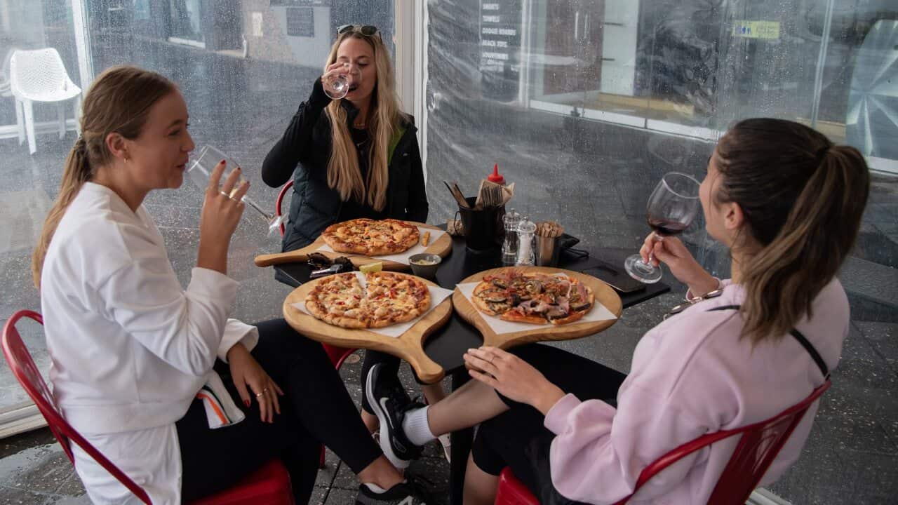 A group of women eating pizza and drinking wine at a restaurant in Bondi Beach, Sydney.