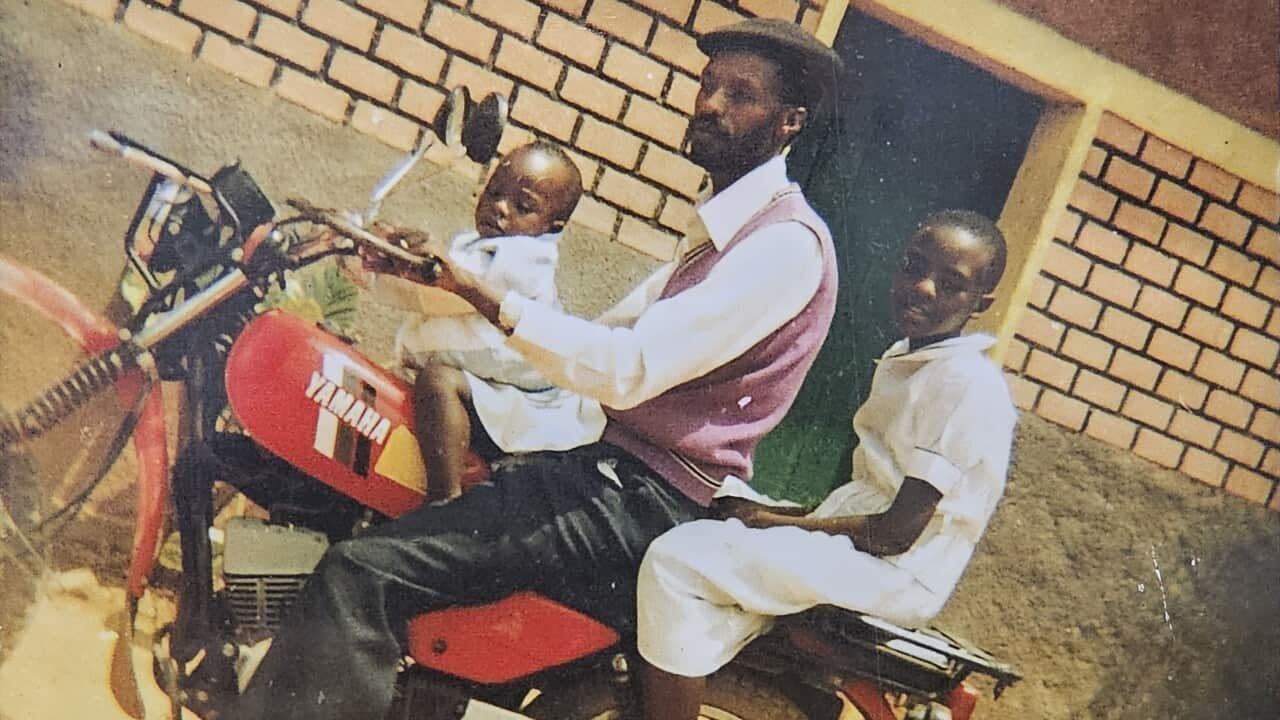 A man and two young children sit on a red motorbike