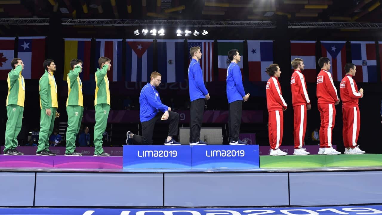 US fencer Race Imboden kneels during his team's foil medal ceremony to protest racial and social injustice.