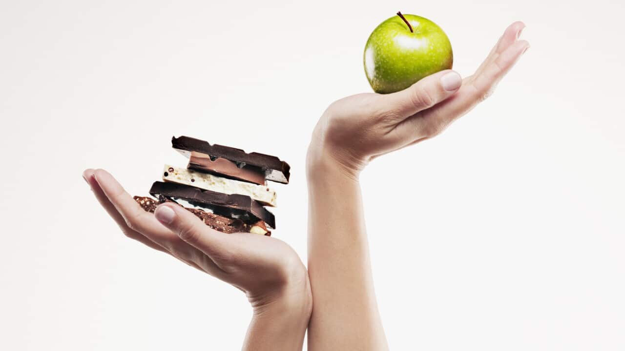 Woman cupping green apple above chocolate bars