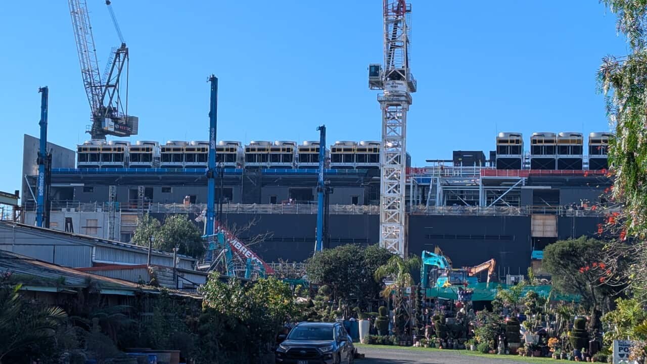 A large building under construction in a suburban street.