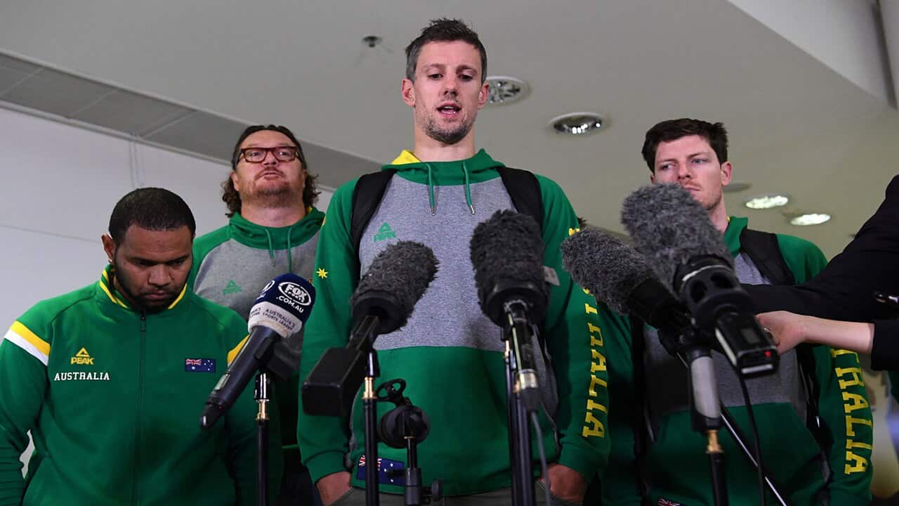 Daniel Kickert of the Boomers, the Australian national basketball team (centre), speaks to the media as he arrives at Brisbane airport, Wednesday, July 4, 2018
