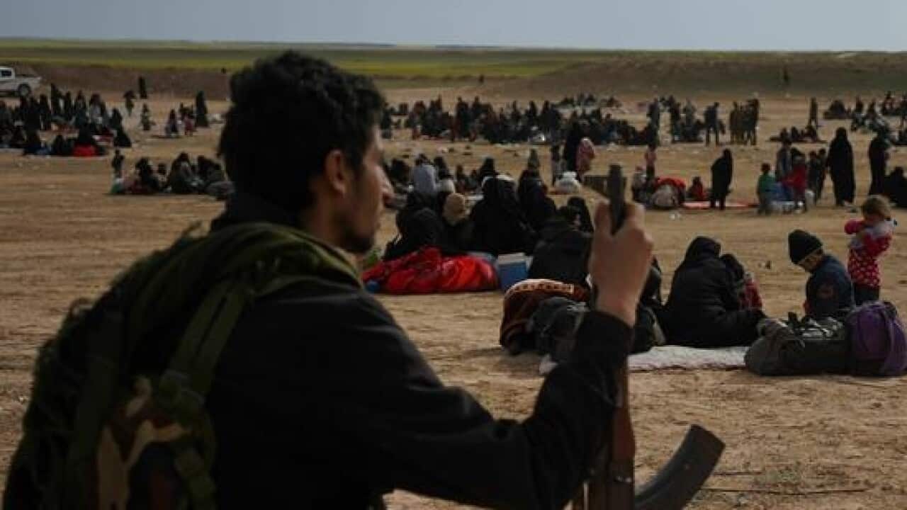 An SDF member watches over people evacuated.