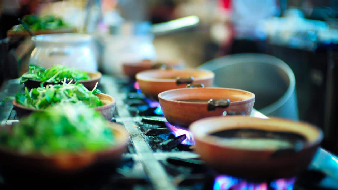 Prepared salad bows and hot pots on burners in a restaurant kitchen