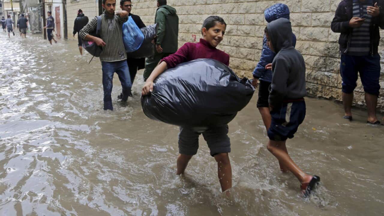 Palestinians carry their belongings in floodwaters
