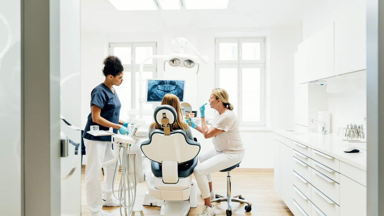 Orthodontist Showing Patient X-Ray Of Teeth In Surgery