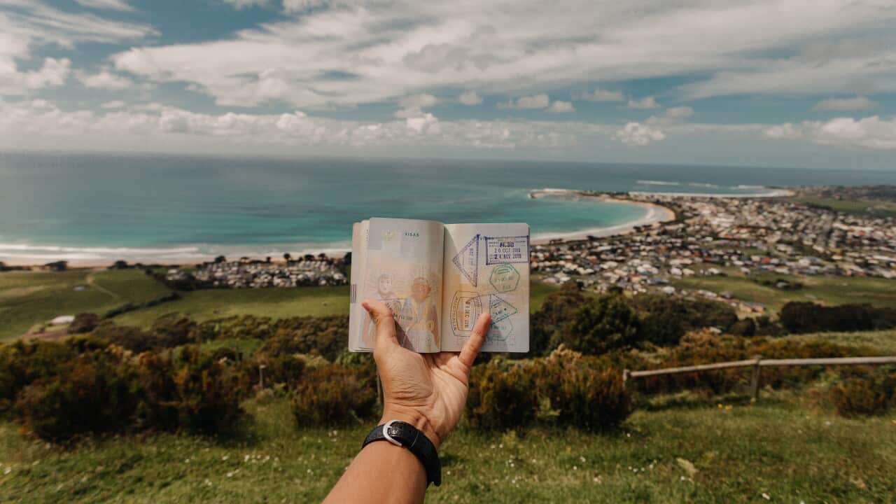 Close-up Hand Holding Passport against beach