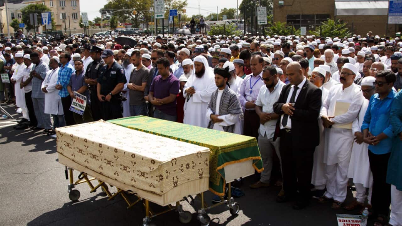 Community members participate in a funeral prayer for a imam