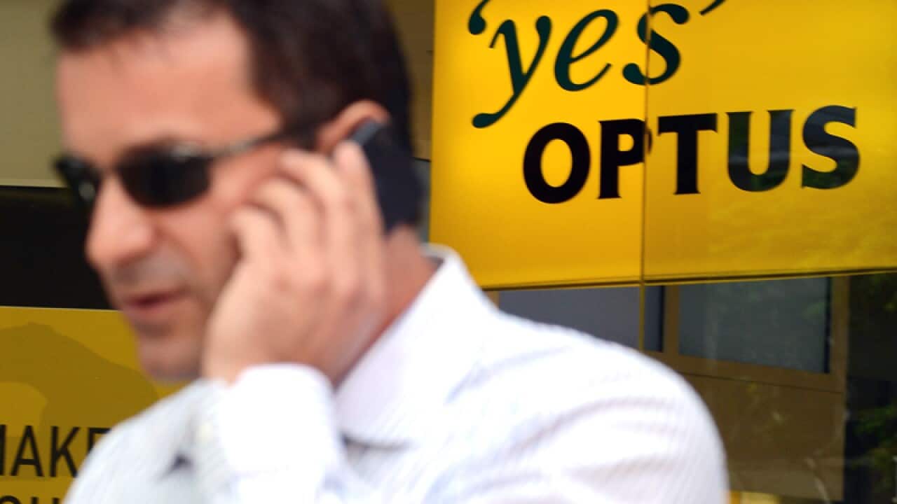 A person talks on his mobile phone next to an Optus shop in Brisbane