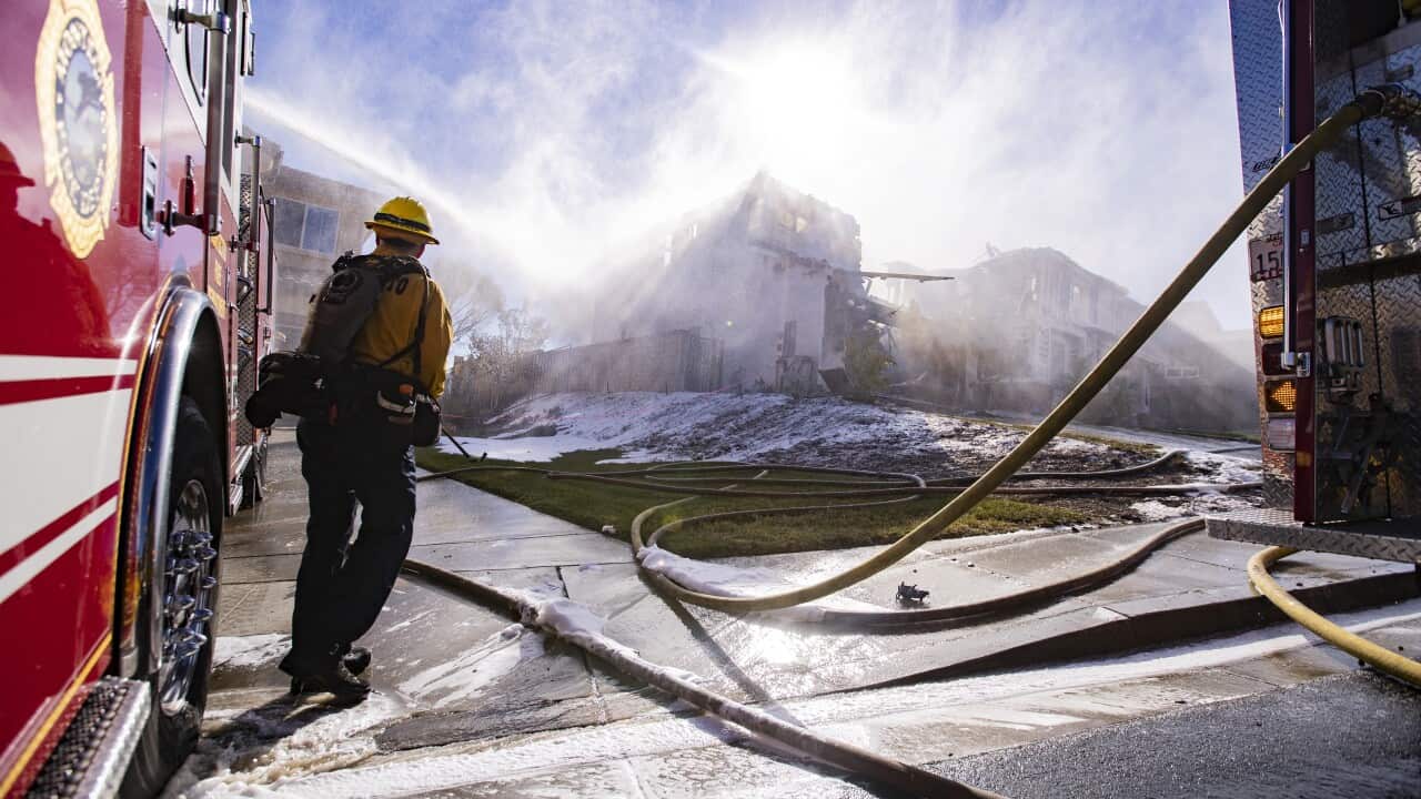 Firefighters extinguish a house set on fire by the Tick Fire in a neighborhood near Santa Clarita, California.